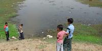 汚染された池のまわりで遊ぶ子どもたち　(C)Amnesty International