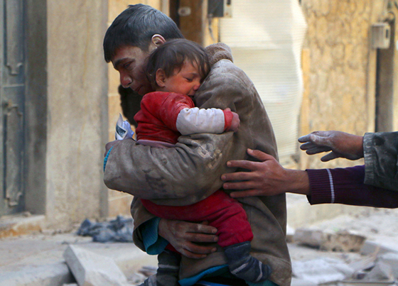 写真：空爆によって破壊された建物のがれきから救い出された妹を抱きしめる少年。2014年2月14日、アレッポ。　© REUTERS/Hosam Katan