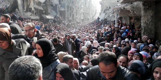 Residents wait to receive UNRWA food aid at the besieged al-Yarmouk camp on January 31, 2014.(C)unrwa.org