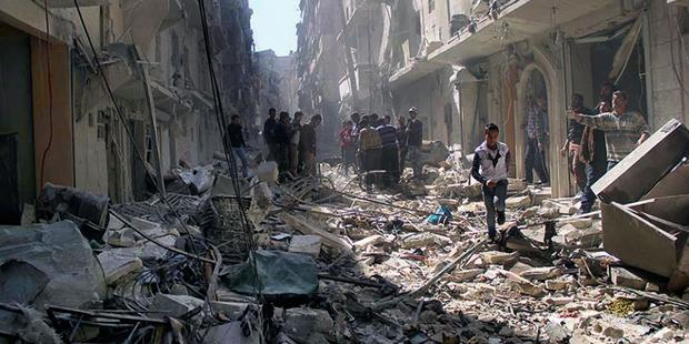 Syrians inspect the rubble of destroyed buildings following a Syrian government airstrike in Aleppo, March 2014.(C) AP Photo/Aleppo Media Center AMC