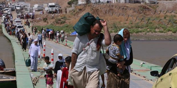 Displaced Iraqis from the Yezidi community cross the Iraqi-Syrian border along the Fishkhabur bridge in northern Iraq.(C)AHMAD AL-RUBAYE/AFP/Getty Images