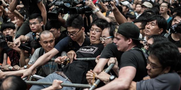 A pro-democracy protester (R) holds onto a barrier as he and others protect a barricade from rival protest groups in the Mongkok district of Hong Kong